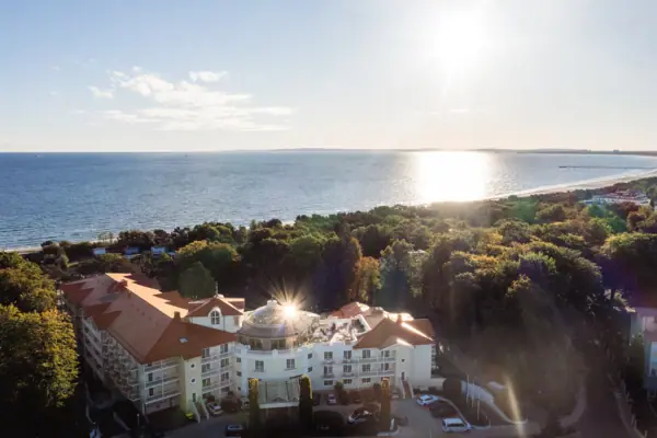 Ein Gebäude mit Bäumen und Wasser im Hintergrund.