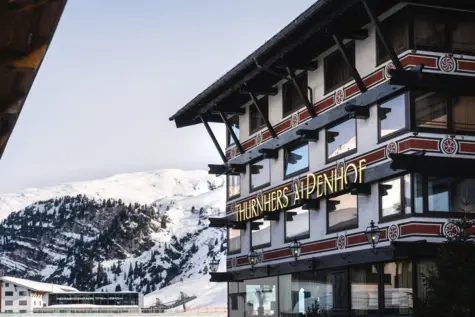 Ein Gebäude mit einem Schild an der Seite, umgeben von Schnee und Bergen.