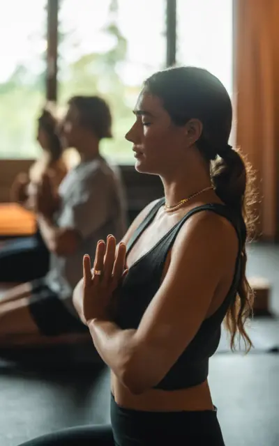 Frau in schwarzem Tanktop in Yoga-Pose mit zusammengelegten Händen vor sich.