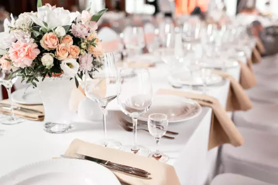 Ein elegant gedeckter Hochzeitstisch mit Blumensträußen in der Mitte. 