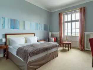 Ein Hotelzimmer mit einem großen Bett steht an einer blauen Wand.