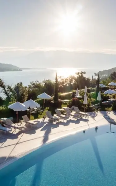 Ein Swimmingpool mit Liegestühlen und Sonnenschirmen am Wasser.