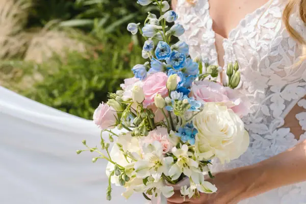 Hochzeit am Tegernsee Eine Frau in einem weißen Kleid hält einen Blumenstrauß.