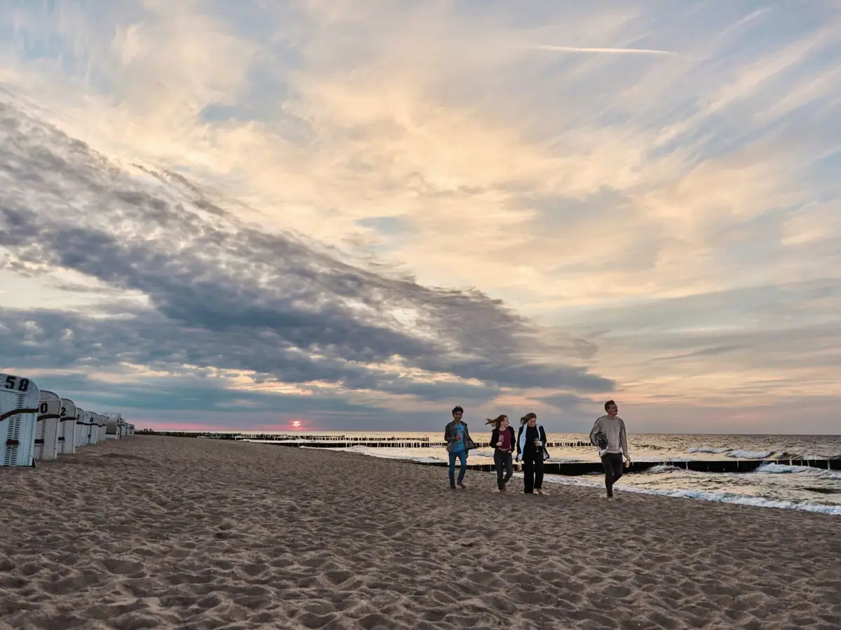 Eine Gruppe von Menschen spaziert am Strand entlang.