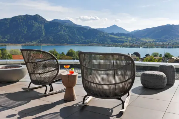 Rooftop Bar Ein Stuhl und Tisch auf der NI BAR Rooftop-Terrasseck auf einen See.