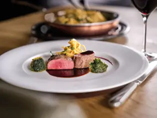 Teller mit Essen und Weinglas auf einem Tisch.