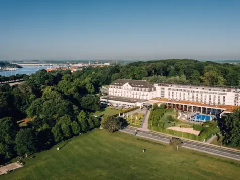 Ein großes weißes Gebäude mit Pool und Bäumen im Hintergrund.