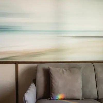 Couch mit Kissen vor verschwommenem Strandbild im Hintergrund