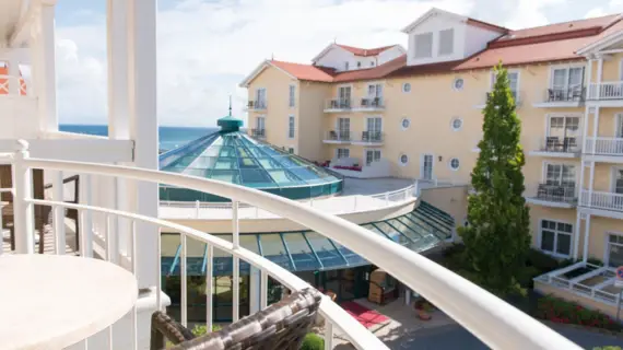 Blick von einem Balkon auf ein großes gelbes Hotelgebäude mit einer Glaskuppel.