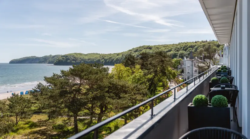 Die Aussicht auf das angrenzende Meer von einem Balkon und den zwischen dem Hotel und Strand liegenden Dünen und Bäumen. 