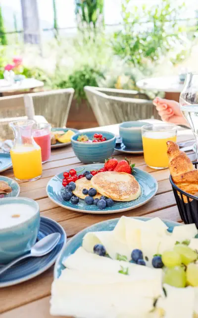 Reich gedeckter Frühstückstisch mit verschiedenen Speisen und Getränken, darunter Gebäck, Obst und Kaffee.