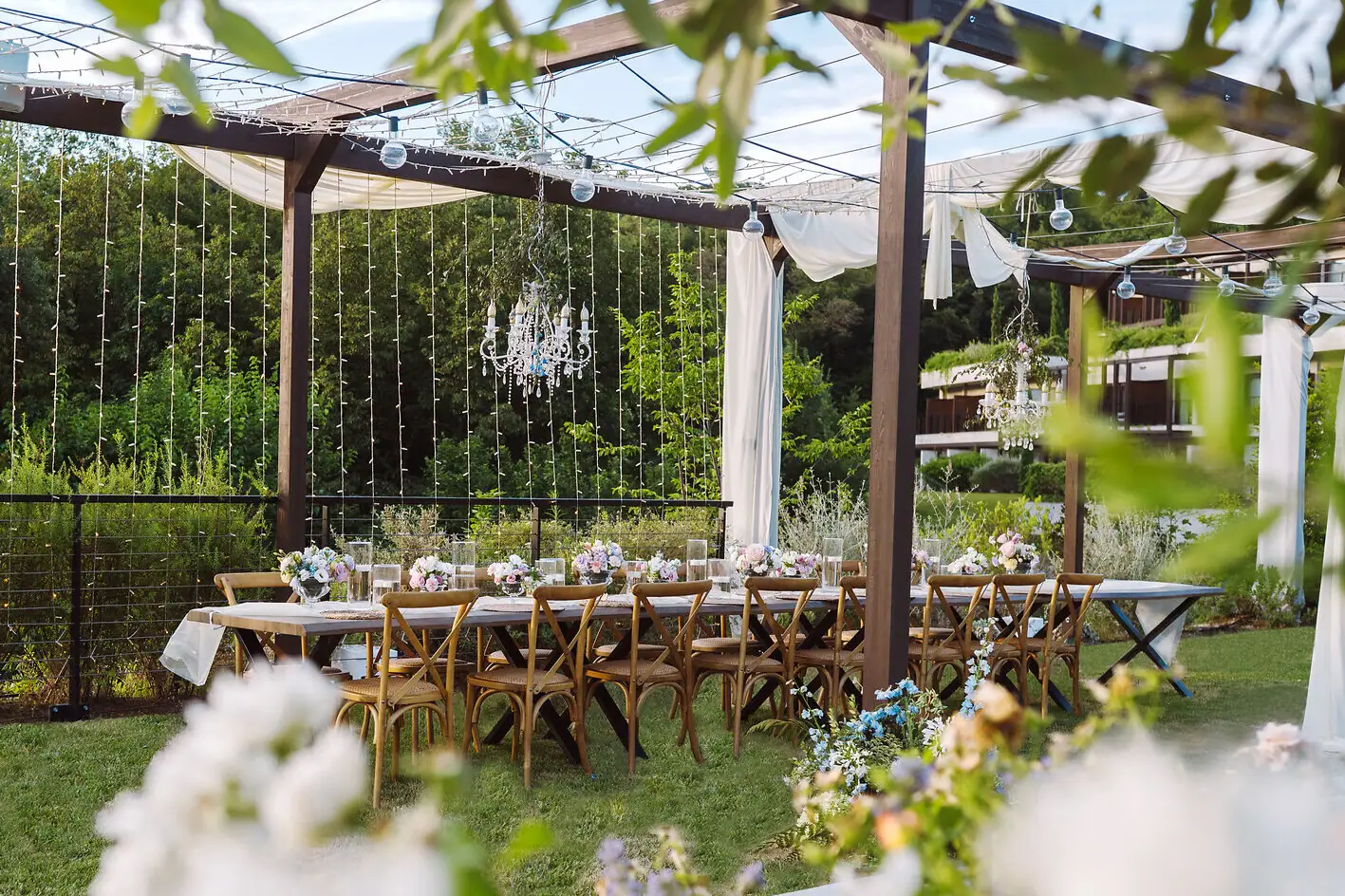Ein für eine Feier langer, gedeckter Tisch im Garten vom Hotel. Der Tisch ist festlich gedeckt und mit Blumen geschmückt.