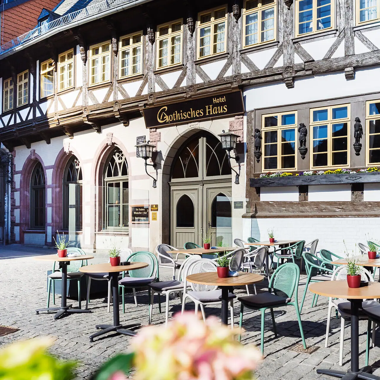 A-ROSA Gothisches Haus Ein Gebäude mit Tischen und Stühlen im Freien.