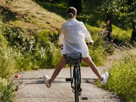 Frau fährt Fahrrad auf einem Weg.