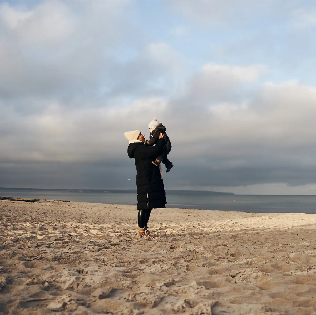 Eine Frau hält ein Baby am Strand.