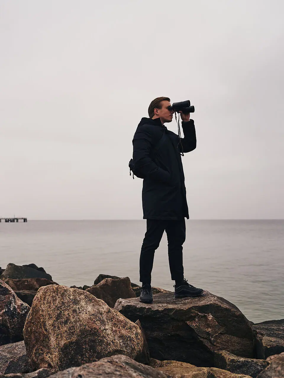 Aktivitäten in Kühlungsborn Ein Mann blickt durch ein Fernglas auf Felsen am Wasser.