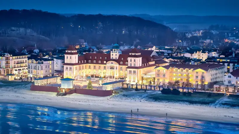 Großes beleuchtetes Gebäude am Strand bei Nacht.