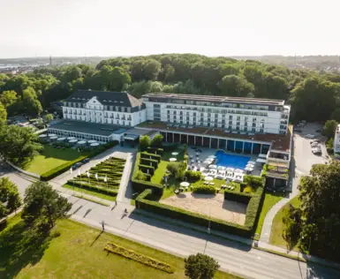 Swimmingpool mit Sonnenschirmen und Stühlen vor einem Gebäude.
