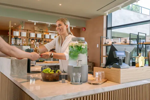 Eine Frau reicht einem Kunden ein Getränk.