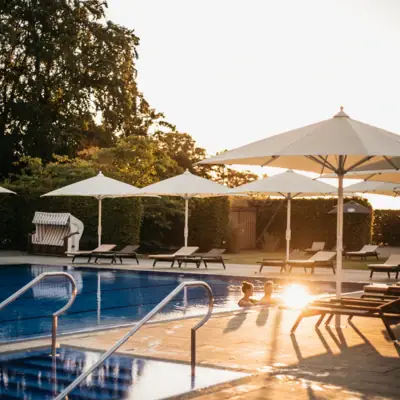 Ein Außenpool mit Sonnenschirmen und Liegestühlen.