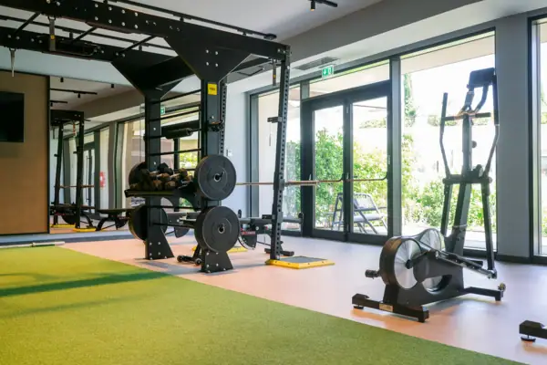 Cardio-Geräte wie Ergometer im Fitnessraum des A-ROSA Gardasee mit Blick ins Grüne.