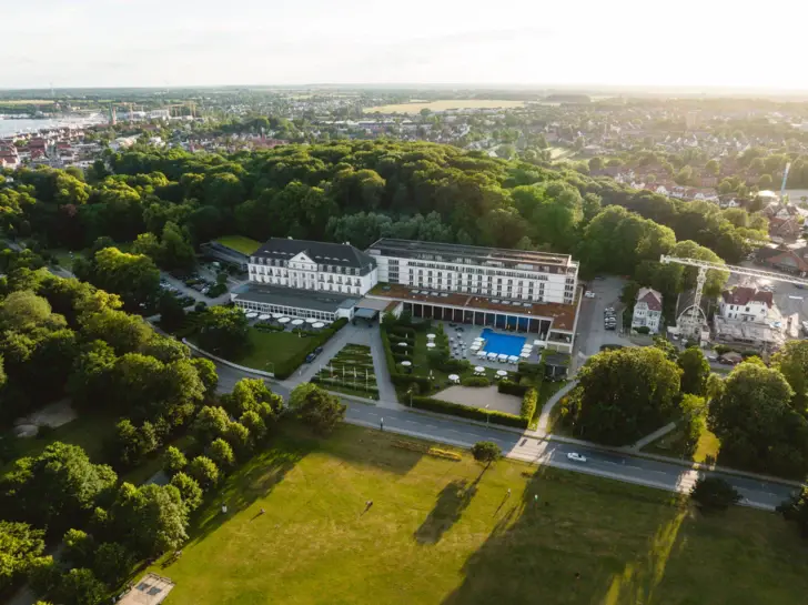 Das A-ROSA Travemünde mit Swimmingpool und umgebenden Bäumen.