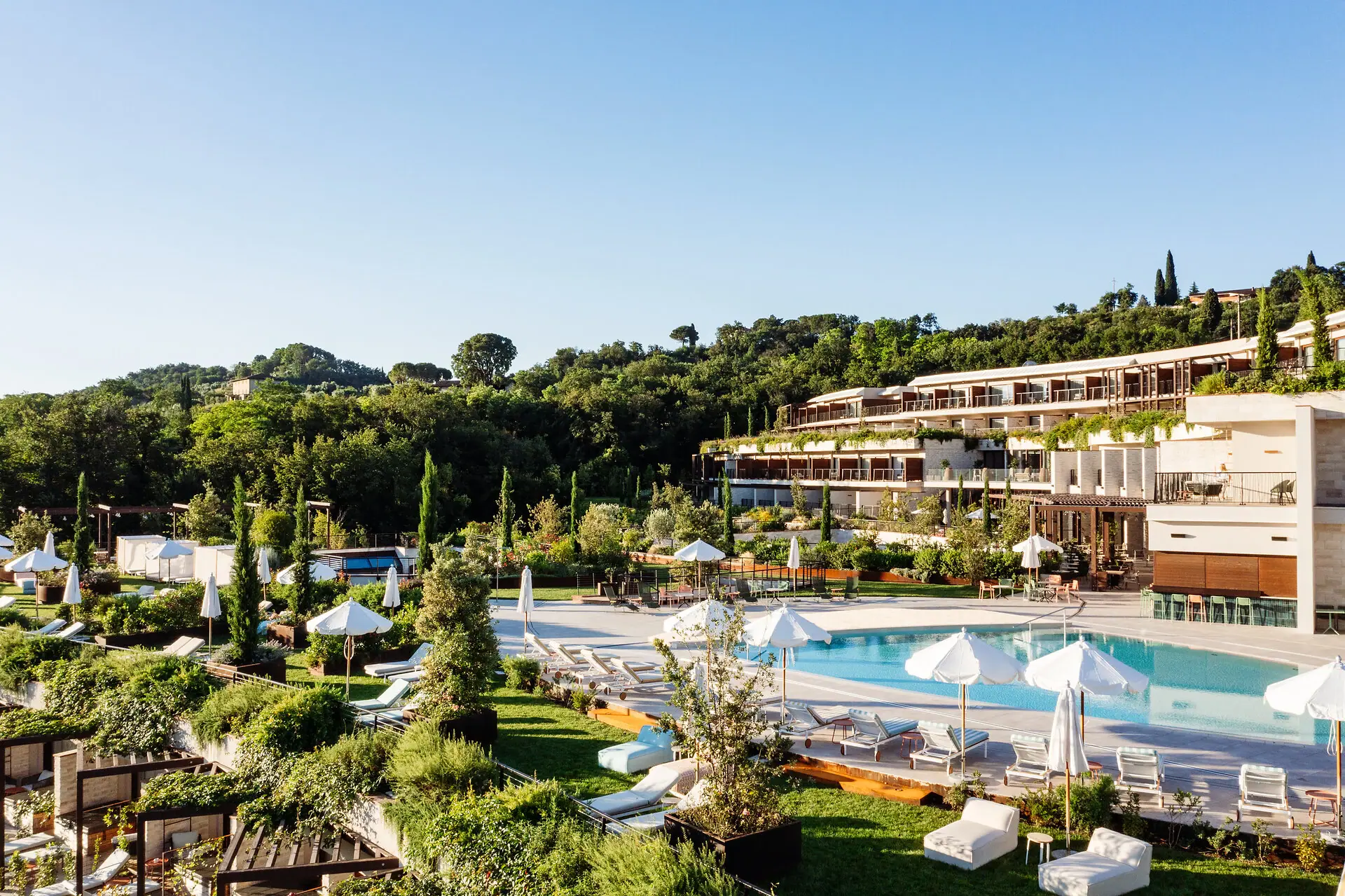 Ein Pool mit Sonnenschirmen und Liegestühlen vor einem Gebäude.