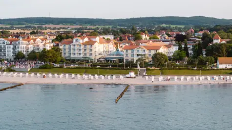 Strand mit Gebäuden und einem Gewässer im Vordergrund.