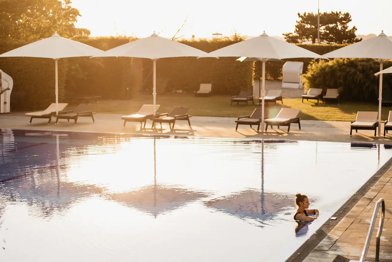 Person im Pool mit Sonnenschirmen im Freien