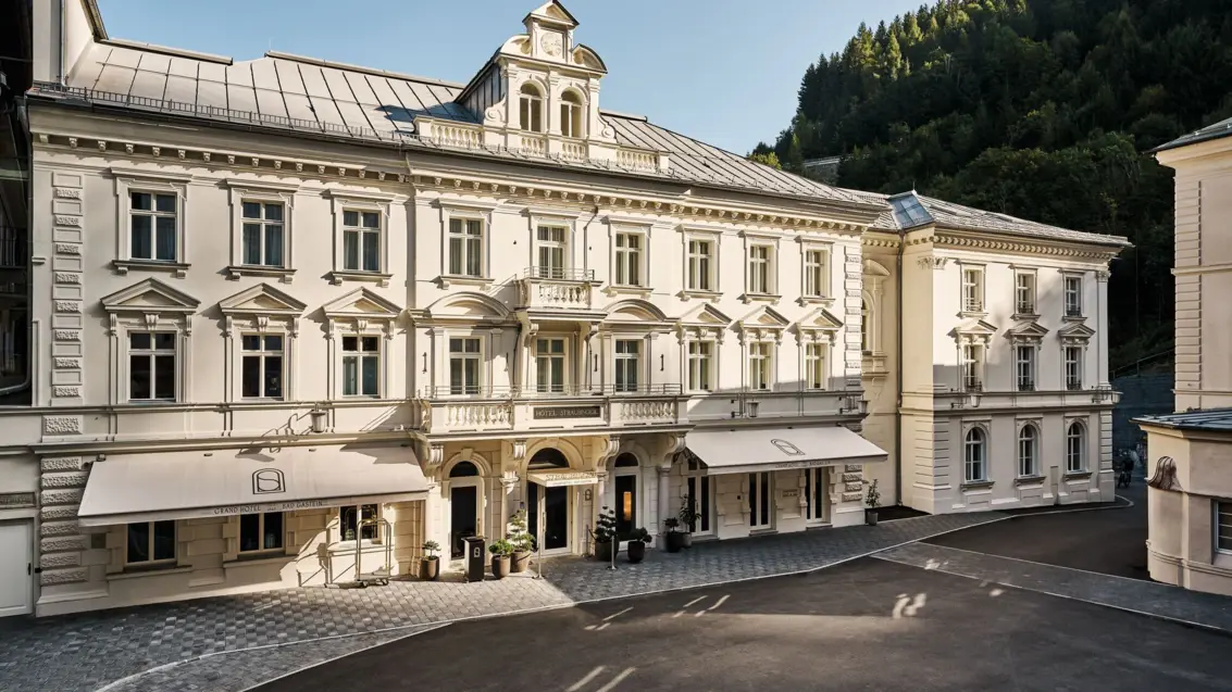 Ein helles altes Gebäude mit vielen Fenstern und zwei Markisen.