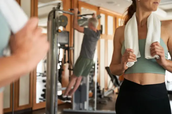 Woman with a towel around her neck standing in the gym.