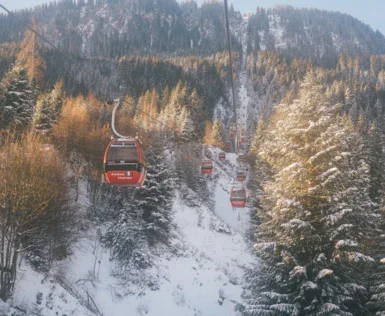 Aus einer Gondel heraus wurden andere Gondeln einer Bergbahn, die einen verschneiten Berg hinauf fahren, fotografiert. 