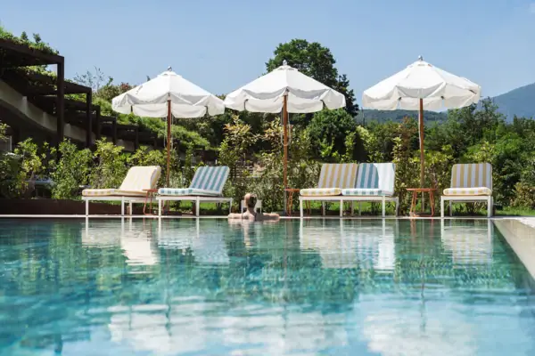 Außenpool im SPA-ROSA des A-ROSA Gardasee mit Liegen und Sonnenschirmen im Gartenbereich.