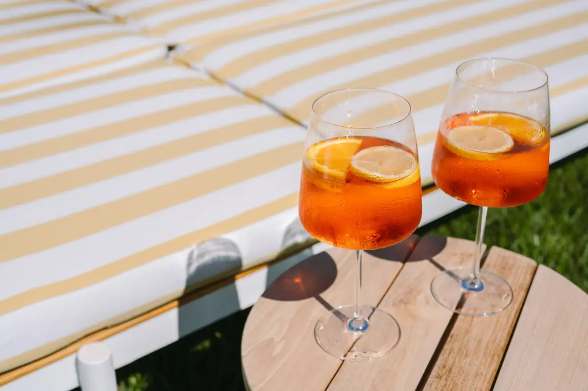 Zwei Gläser mit orangener Flüssigkeit und Zitronenscheiben auf einem Tisch.