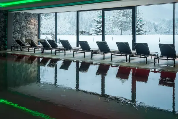 Ein Pool mit Stühlen vor einem großen Fenster.
