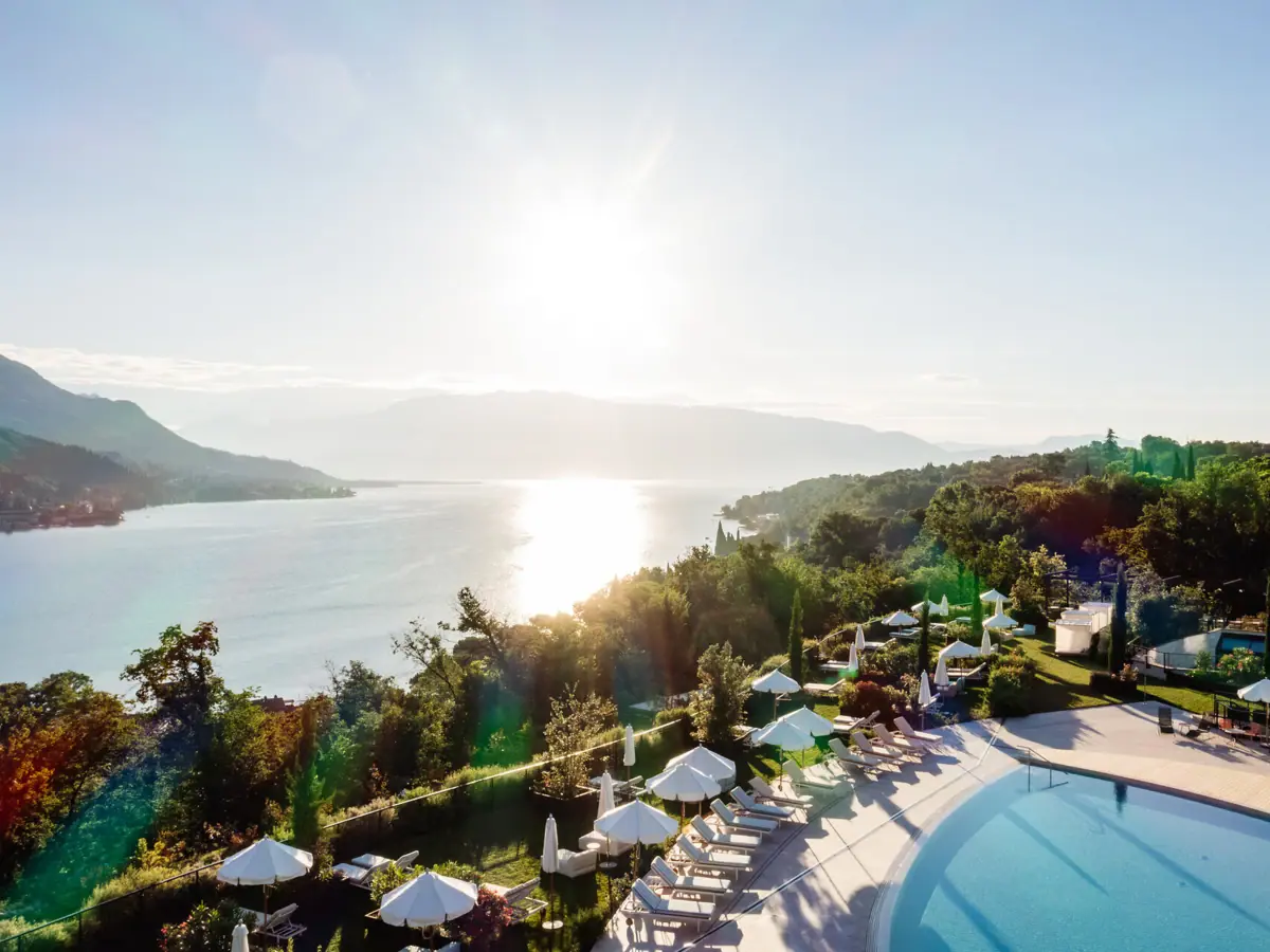 Ein Schwimmbecken mit Sonnenschirmen und Liegestühlen an einem Gewässer.