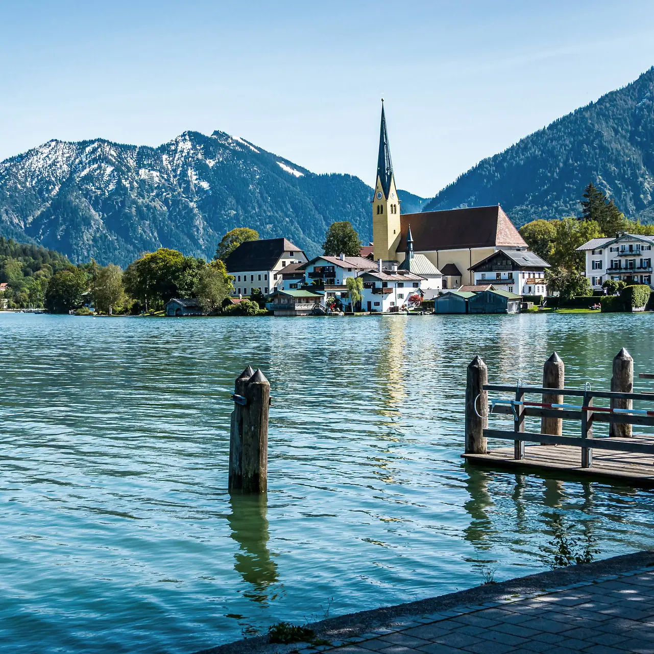 Aktivitäten Ein See mit einer Kirche und Bergen im Hintergrund.