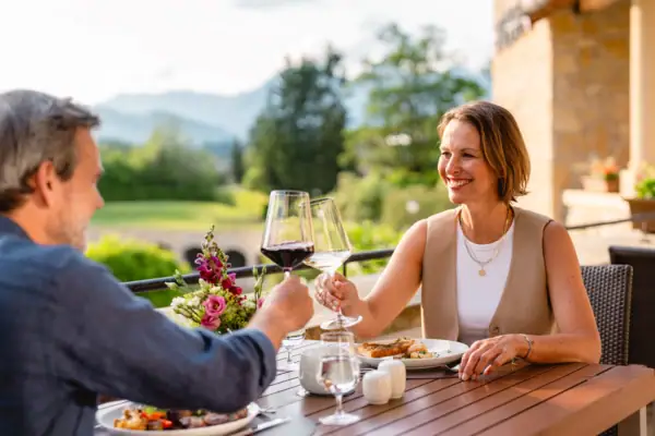 Ein Mann und eine Frau sitzen an einem Tisch mit Essen und Weingläsern.