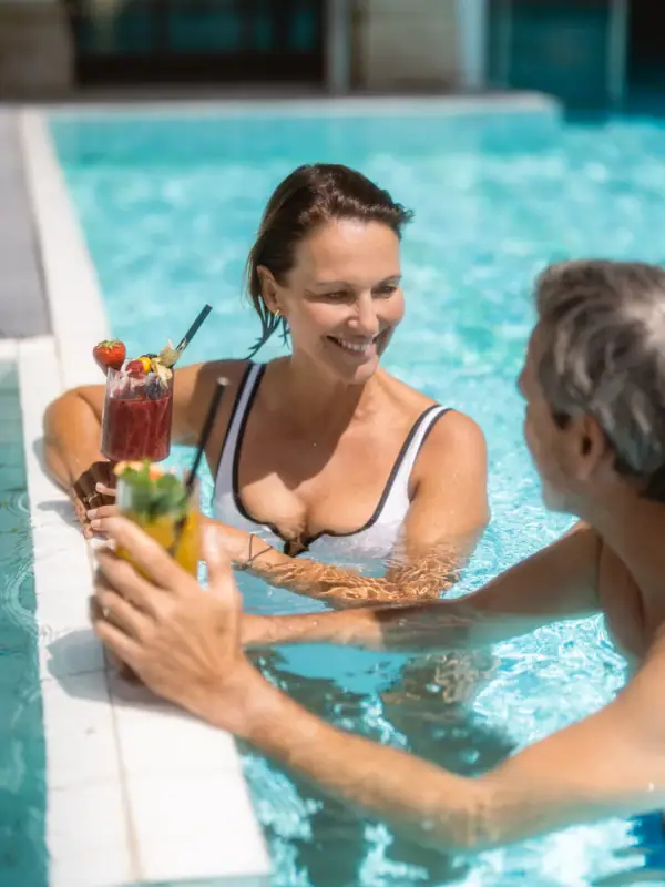 Ein Mann und eine Frau im Pool mit Getränken.