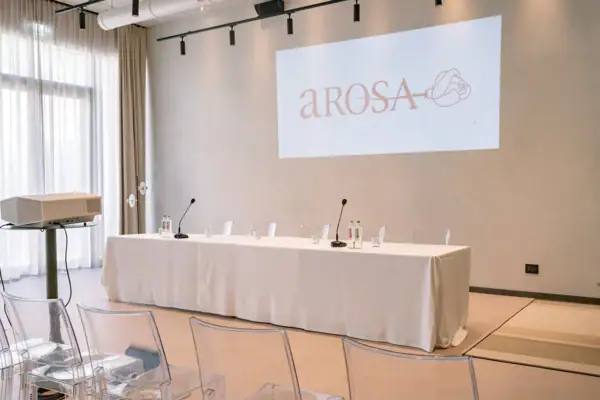 Konferenzraum im A-ROSA Gardasee mit moderner Technik, Leinwand und Mikrofonen.