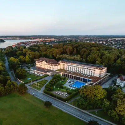 Großes Gebäude mit Pool, umgeben von Bäumen.