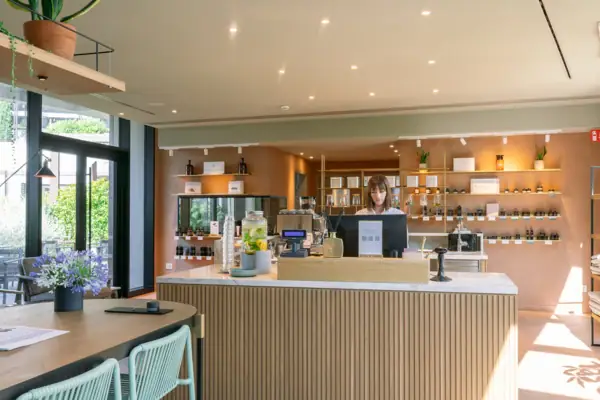 Eine Frau hinter einem Tresen des SPA-ROSA Shops mit Kosmetikprodukten und Accessoires im A-ROSA Gardasee.