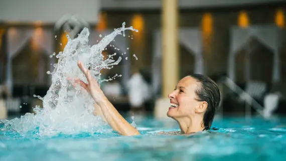 Eine Frau planscht im Wasser eines Innenpools. 