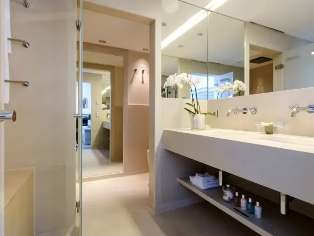 A beige bathroom with two large washbasins next to each other.