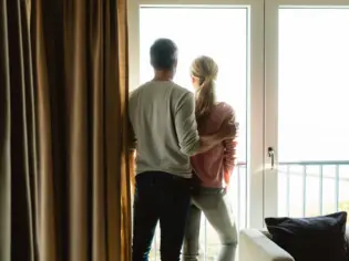 Ein Mann und eine Frau stehen an einem Fenster und schauen hinaus.