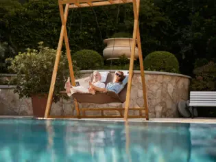 Ein Paar entspannt in einem Hängesessel an einem Pool.