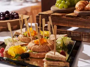 Ein Tablett mit Sandwiches, Obst und verschiedenen Speisen auf einem Tisch.