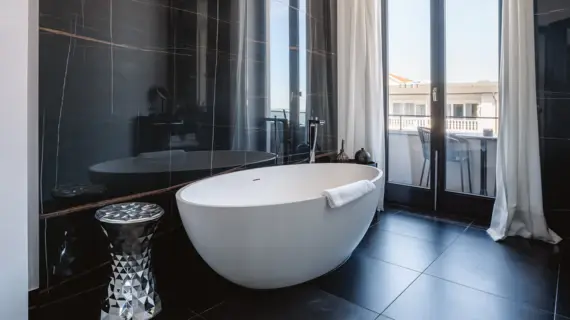 Bathroom with bathtub and shower, equipped with washbasin, mirror and window.