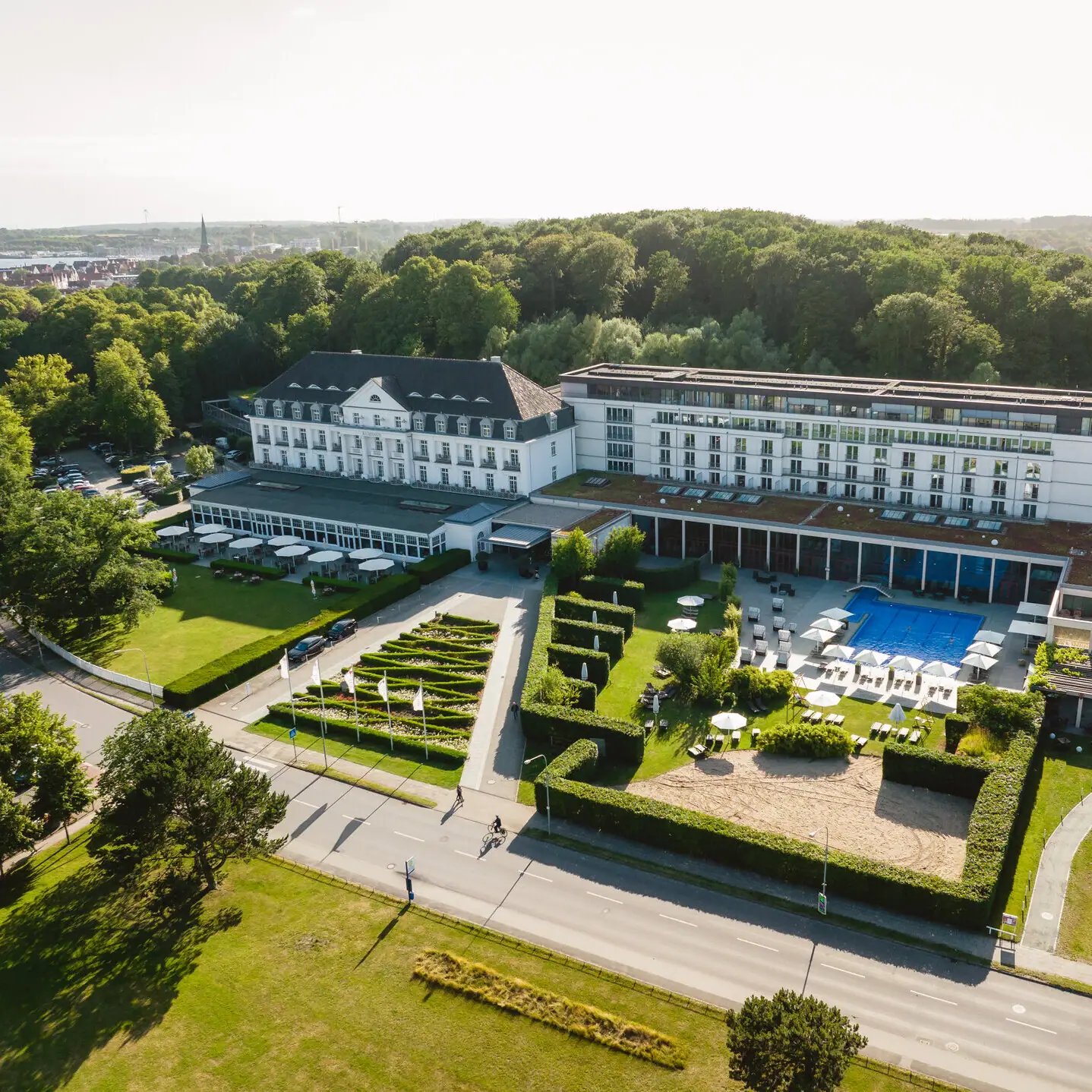 Großes weißes Gebäude mit Pool und Bäumen im Freien.