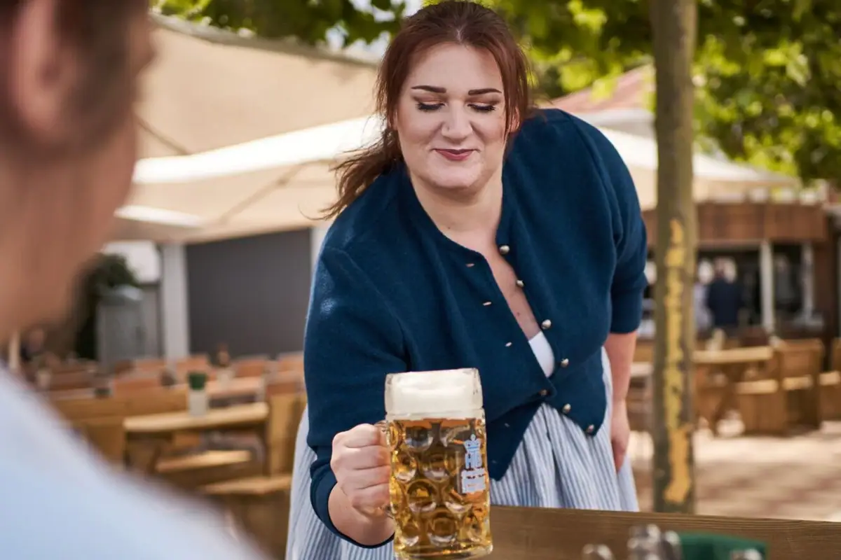 Eine Wirtin serviert eine Maß Bier in einem Biergarten